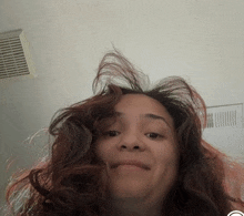 a woman with messy hair looks at the camera with a smile on her face