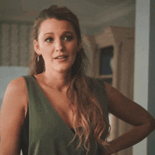 a woman wearing hoop earrings and a green top smiles