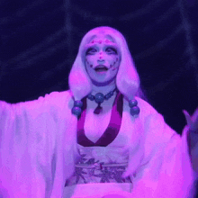 a woman in a white kimono with purple beads on her neck