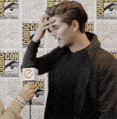 a man is being interviewed in front of a comic con backdrop