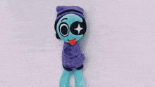 a stuffed alien wearing a purple beanie with a star in its eye