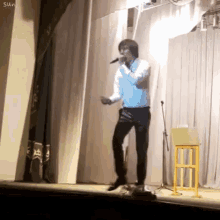a man is singing into a microphone on a stage while dancing .