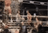 a man is standing in a boxing ring with a referee watching .