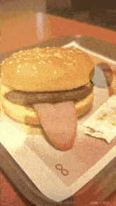 a hamburger with a tongue sticking out sits on a tray with an infinity symbol