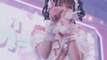 a girl in a maid costume is singing into a microphone on a stage .