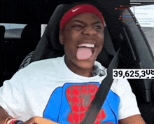 a man wearing a nike headband is sitting in a car with his tongue out ..
