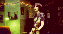 a woman is playing a guitar in a room with a french reverse sign on the wall .