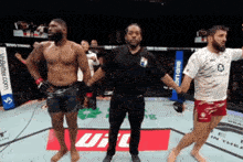 a referee stands between two fighters in a ring with a bud light banner in the background