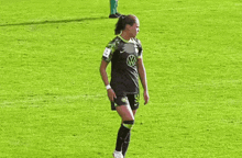 a female soccer player is standing on the field with her hands on her hips