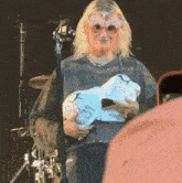 a woman wearing a mask holds a piece of paper with the name emily on it