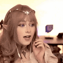 a woman is wearing a crown on her head and headphones while talking on a cell phone .