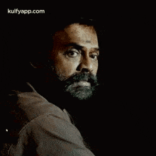 a man with a beard and a tattoo on his forehead is looking at the camera .