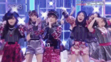a group of girls are dancing on a stage with akb48 written on the bottom