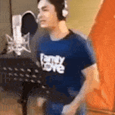 a man wearing headphones is singing into a microphone while wearing a family love shirt .