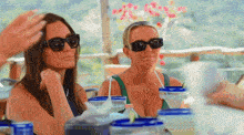two women wearing sunglasses are sitting at a table