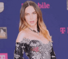 a woman in a black and silver dress stands in front of a t mobile sign