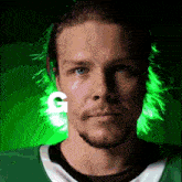 a close up of a man 's face with a green background and a white letter g