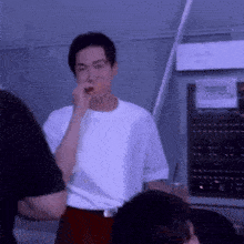 a man in a white t-shirt is eating a piece of food while standing in a room .