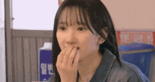 a young woman is covering her mouth with her hand in a restaurant .