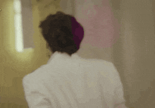 a man in a white jacket is standing in front of a mirror and looking at himself .