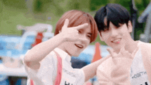 two young men are posing for a picture and making a peace sign with their hands .