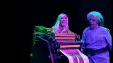 a man and a woman are standing next to each other on a stage in a dark room .