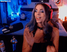 a woman wearing headphones stands in front of a shure microphone in a bedroom