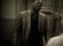 a man in a brown leather jacket stands in front of a shelf with boxes on it that says p on it