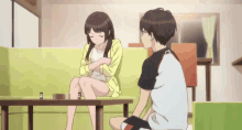 a boy and a girl are sitting on a couch in a living room talking to each other .