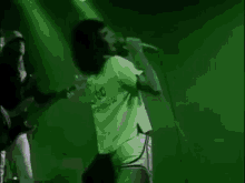 a man is singing into a microphone while another man plays a guitar on stage .