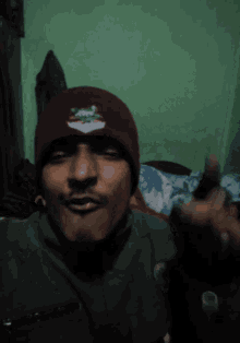 a man wearing a red beanie with a white emblem on it