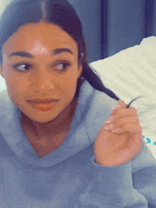 a woman in a blue tie dye sweatshirt is holding her hair