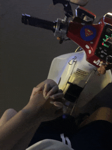 a person holding hands with a superman sticker on the handlebars of a motorcycle
