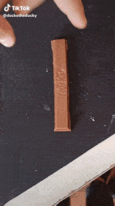 a person is holding a kitkat bar on a black surface
