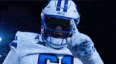 a football player wearing a helmet and gloves giving a thumbs up .