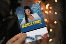 a person holding a card that says jamilia grier show on it