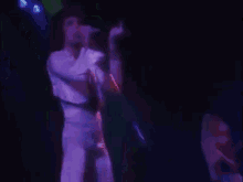 a woman in a white dress is singing into a microphone on a stage .