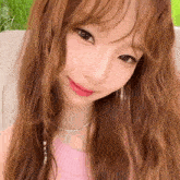 a close up of a woman 's face wearing a pink top