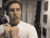 a man in a white shirt is adjusting his tie .
