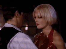 a man and a woman are standing next to each other and kissing . the woman is wearing a red dress .