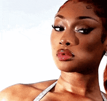 a close up of a woman 's face with a white background . she is wearing a bikini top and earrings .