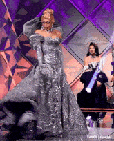a woman in a long silver dress is dancing on a stage .