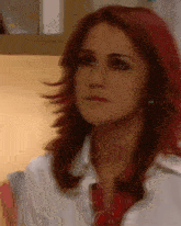 a woman with red hair is wearing a white shirt and red tie .