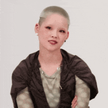 a woman with a shaved head is wearing earrings and a jacket