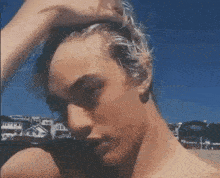 a close up of a man 's face with his hand in his hair .