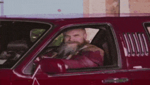 a man with a beard is driving a red truck