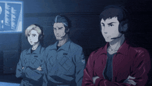 a man wearing a headset stands next to a woman and a man wearing a red jacket