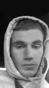 a black and white photo of a man wearing a hoodie and holding a cup