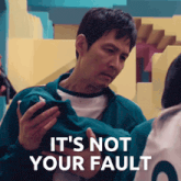 a man holding a cell phone with the words " it 's not your fault " below him