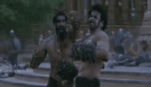 a couple of men are standing next to each other without shirts on .